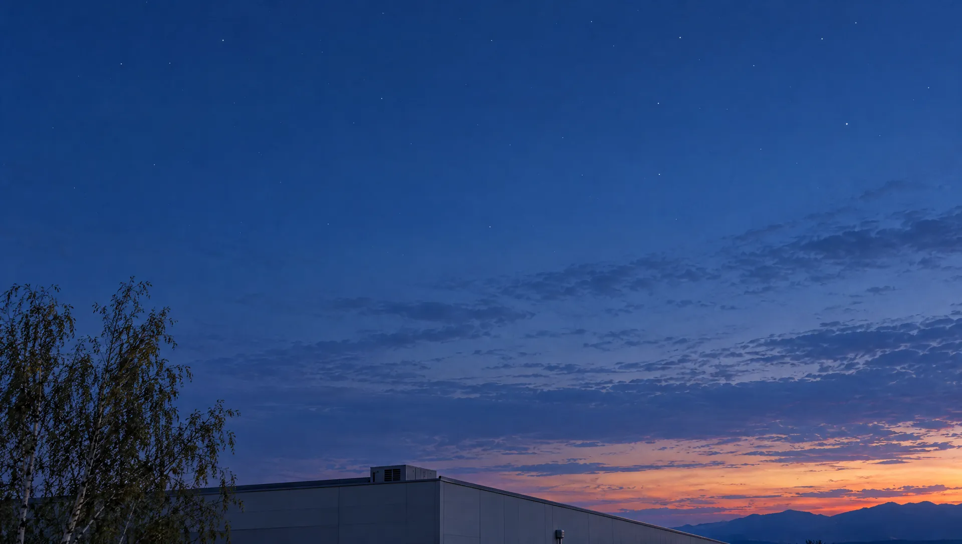 Il cielo al crepuscolo sopra il tetto dell'azienda, con le Prealpi all'orizzonte.